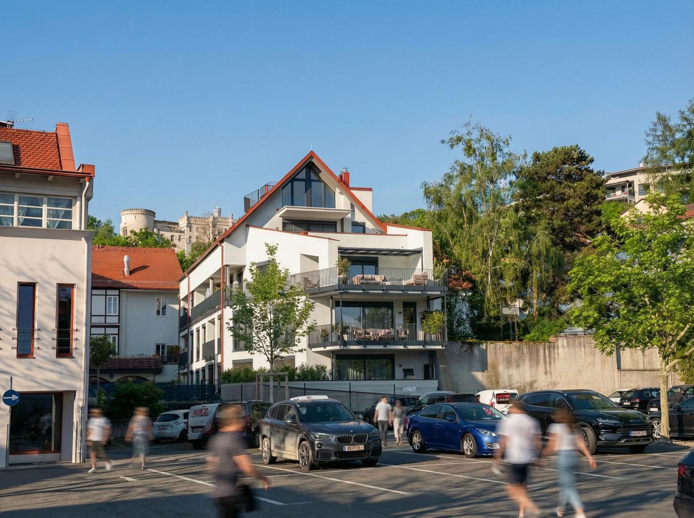 Moserhof, Giebelansicht vom Parkplatz mit Balkonen und Burg im Hintergrund